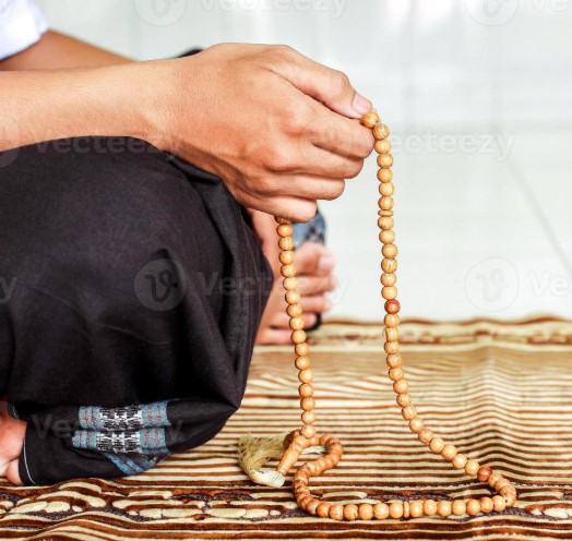 Person holding tasbih prayer beads during dhikr prayer