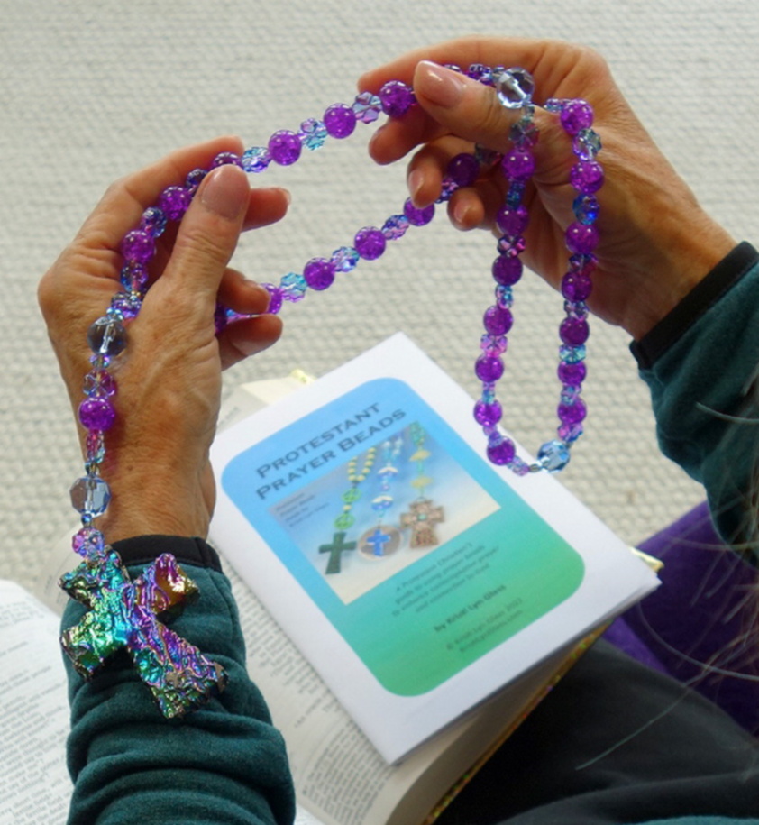 Hands holding Protestant prayer beads above how-to booklet