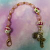 Pink Roses Protestant chaplet bracelet with rose ceramic beads, pink cat’s-eye glass, goldtone metal cross, and BE STILL AND KNOW pendant